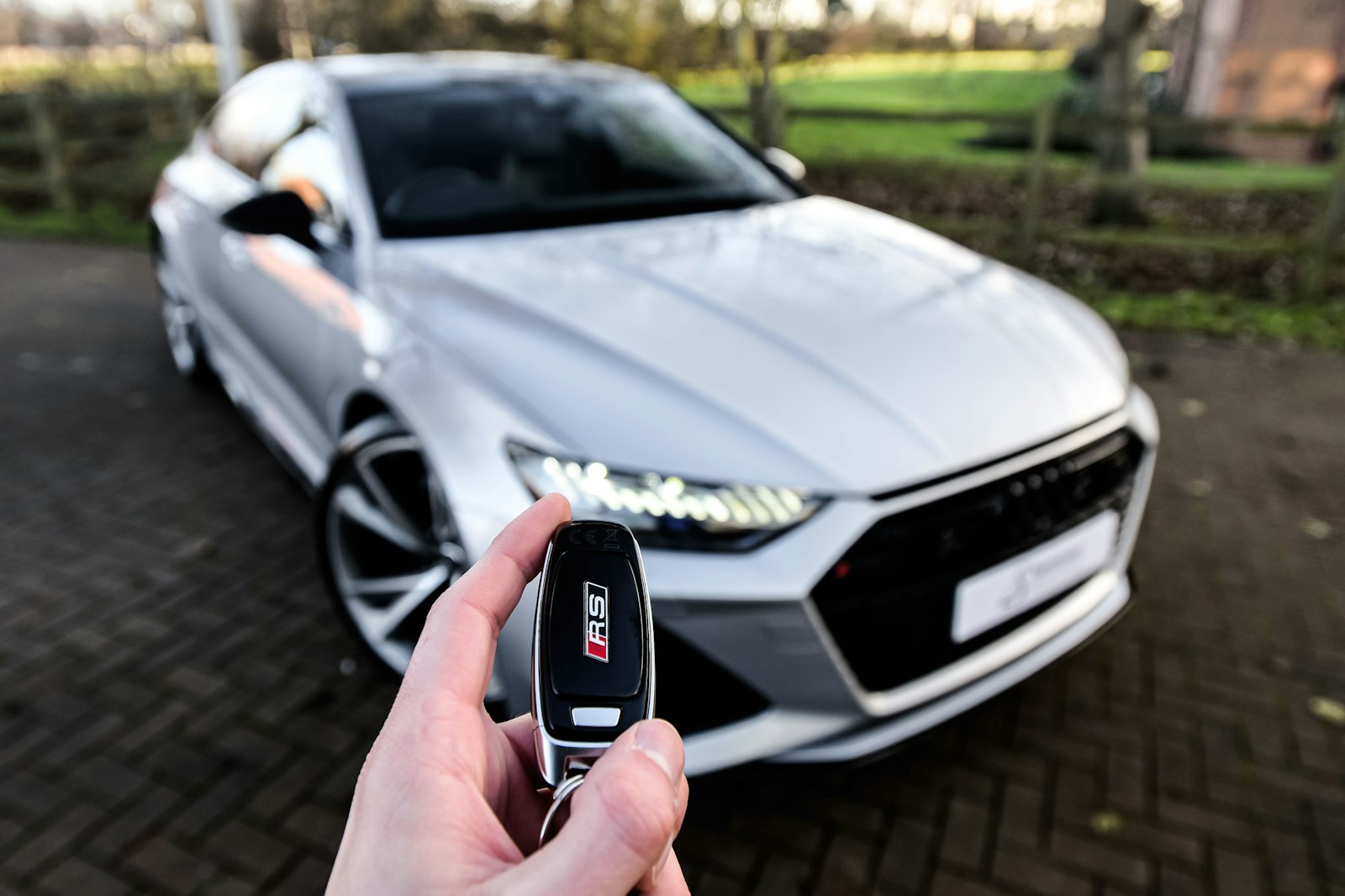 Autoschlüssel mit Funkfernbedienung wird vor einem Fahrzeug gehalten
