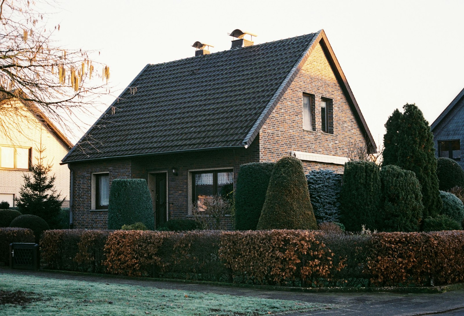 Freistehendes Wohnhaus hinter einer geschnittenen Hecke