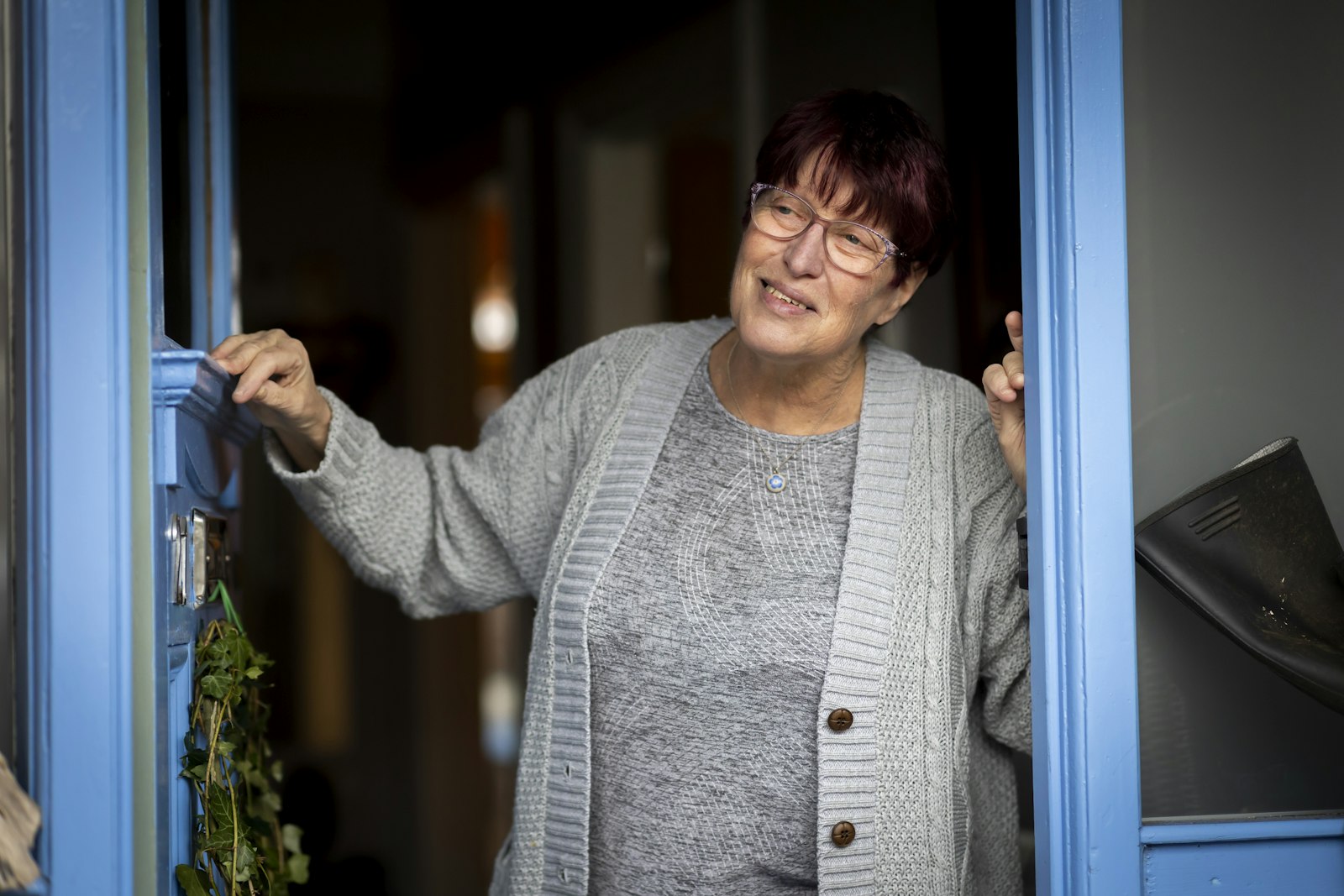 Frau öffnet lächelnd eine Haustür