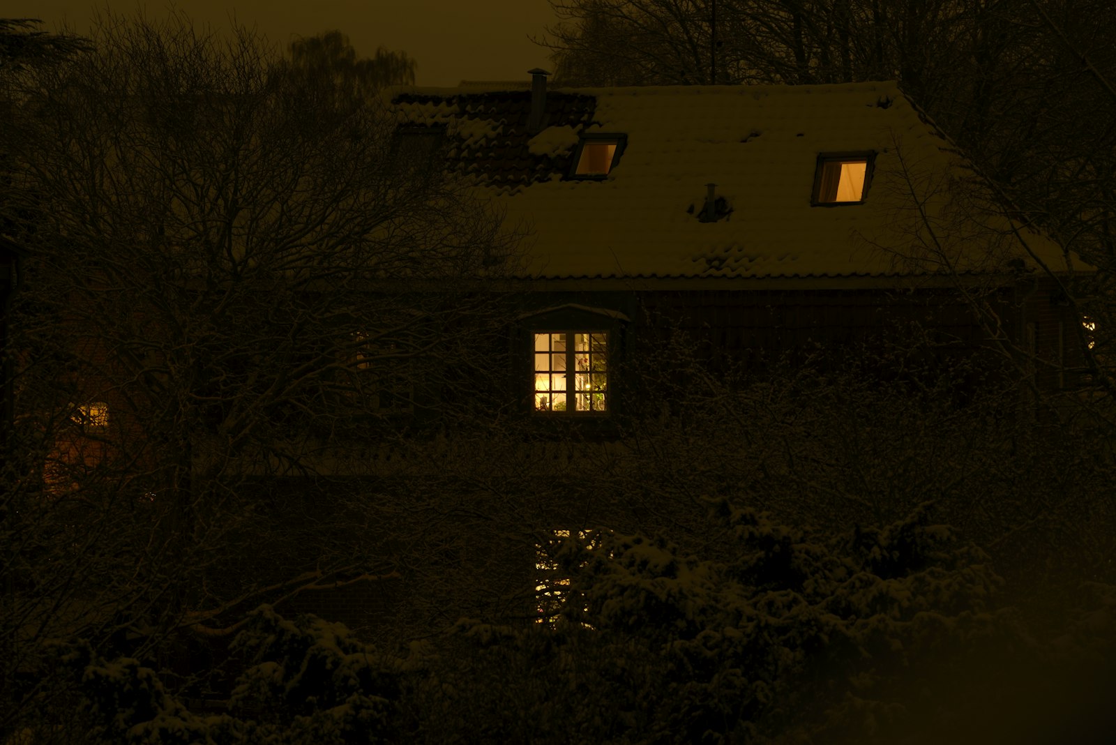 Einfamilienhaus am Abend mit beleuchteten Fenstern